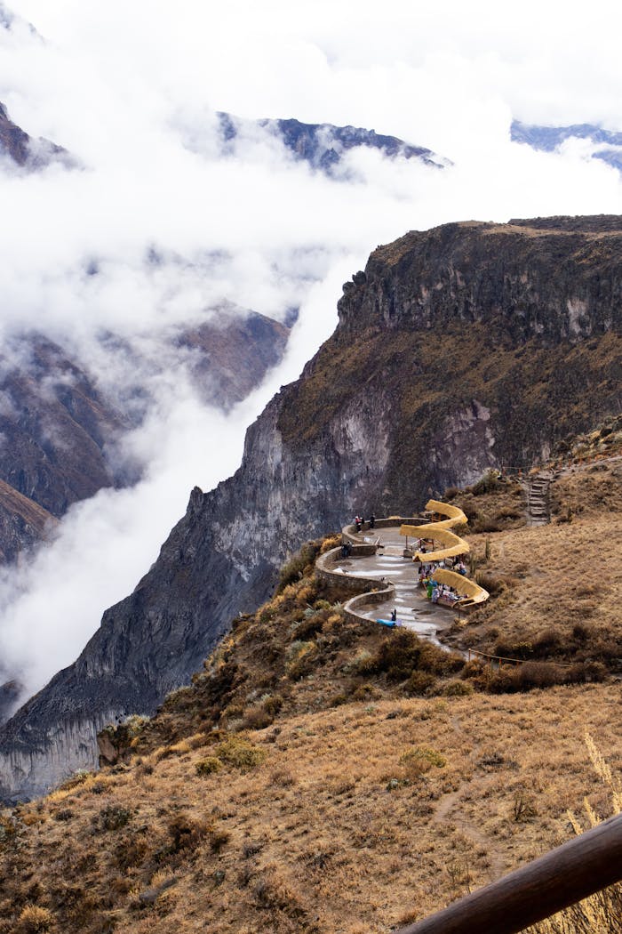 Breathtaking aerial view of Colca Canyon with scenic observation platforms and clouds.